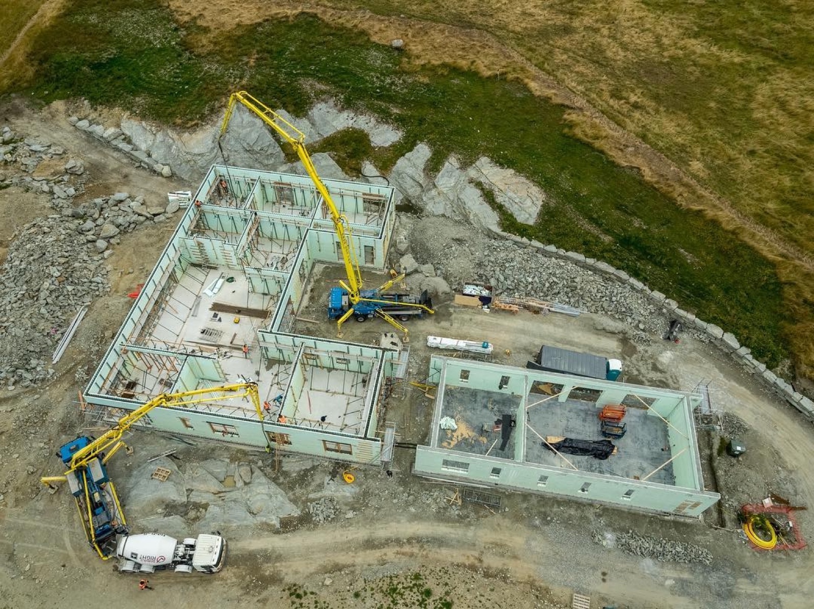 Te Toka — aerial view during concrete pour, two cranes, Lake Wakatipu